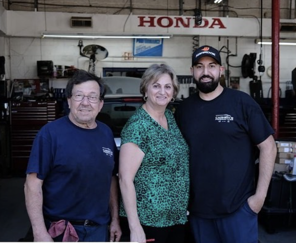 The Finocchiaro family standing together under the Honda sign in the Cranford shop
