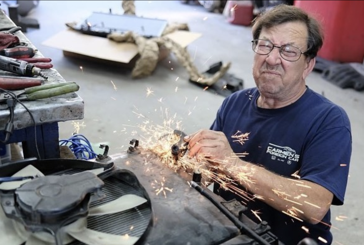 Carmen Finocchiaro grinding a bracket at the bench, sparks flying, inside Carmen's Foreign Car Repair