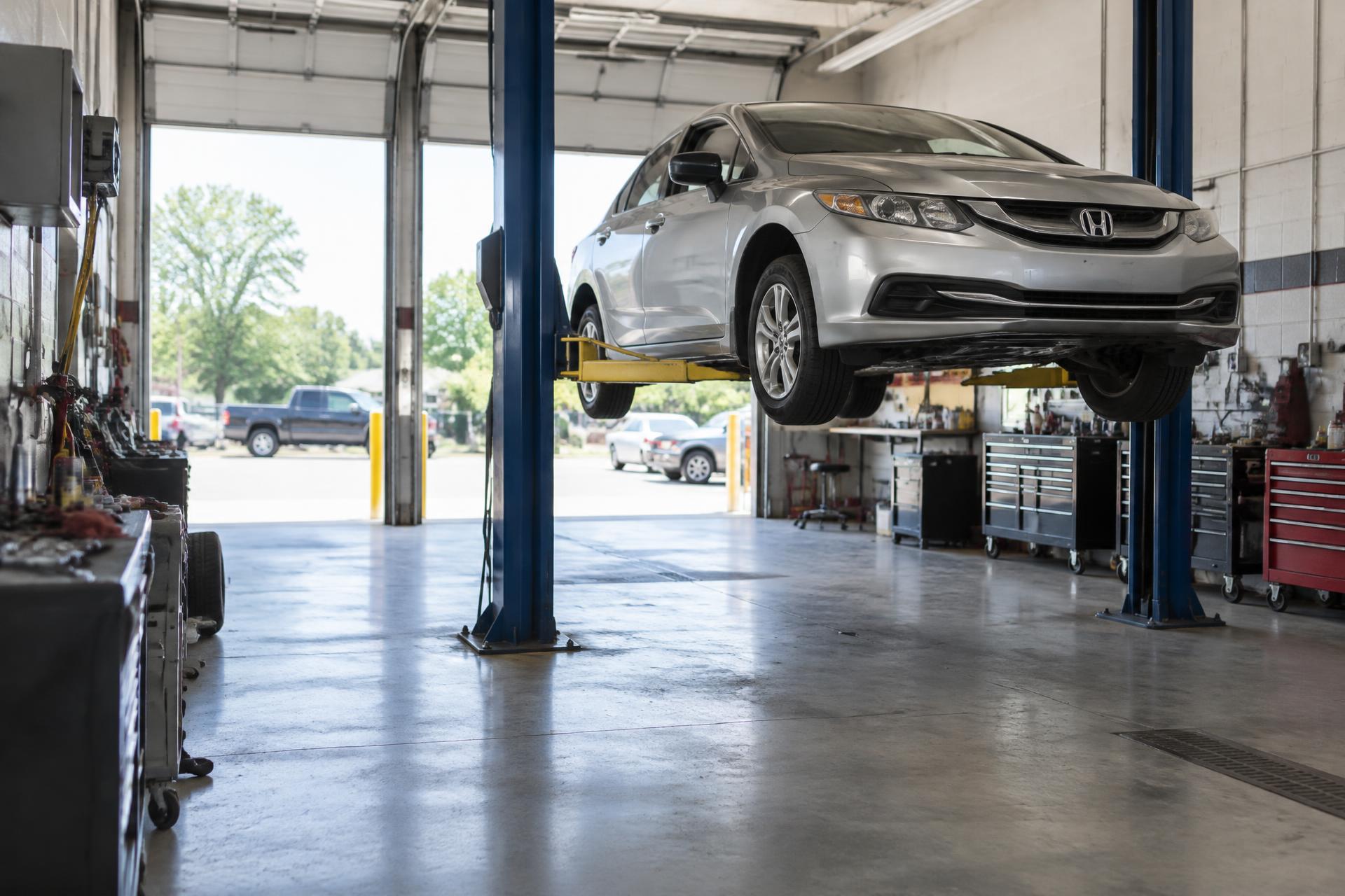 Honda sedan raised on a lift inside Carmen's Foreign Car Repair in Cranford, New Jersey