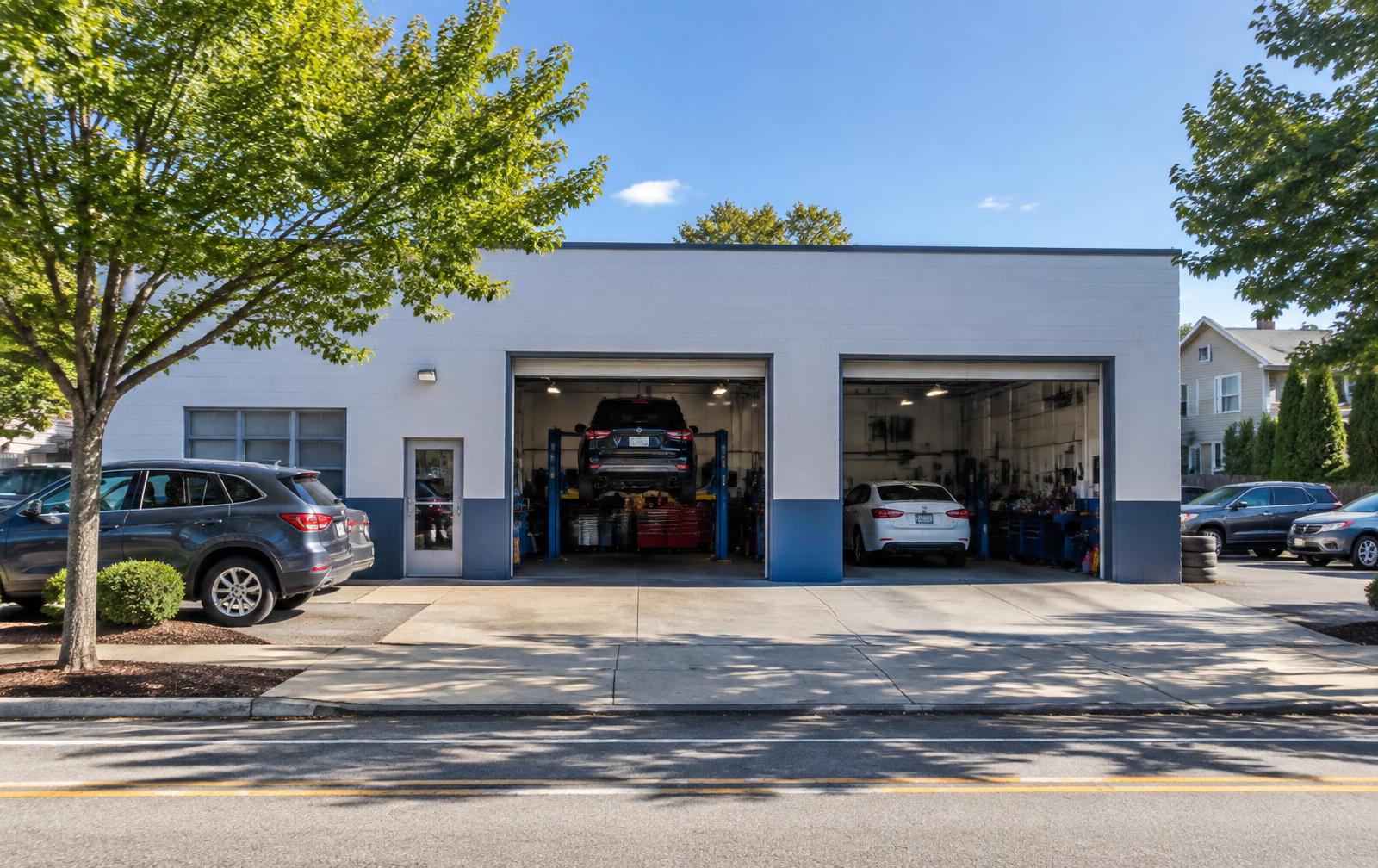 Bay doors open on a bright morning outside an independent auto repair shop